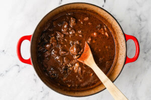 A spoon stirring gravy and beef tips in a pot.