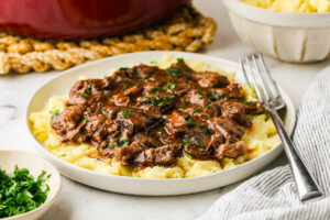 Mashed potatoes with beef and gravy, herbs sprinkled on top, fork beside.