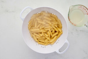 Draining pasta and reserving some pasta water.