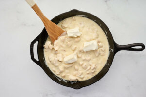 Adding cream cheese to the alfredo sauce.