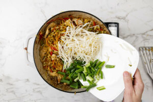 Finishing the noodles with green onions and bean sprouts.