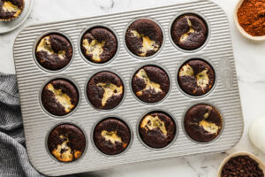 A cupcake pan filled with warm chocolate cream cheese cupcakes.