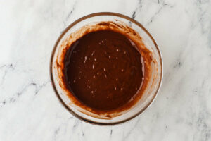Mixing chocolate cupcake batter in a clear bowl.