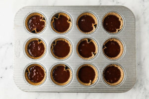 Adding chocolate batter to cupcake liners.