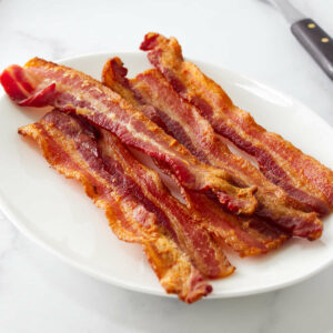 Strips of crisp bacon on a white plate.