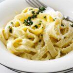 Fettuccini pasta in a bowl with creamy alfredo pasta sauce.
