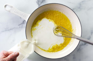 Adding heavy cream to the skillet.