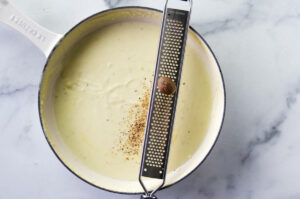 Grating fresh nutmeg into homemade alfredo cream sauce.