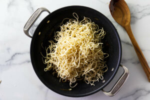 Adding the noodles to the skillet.