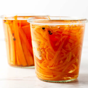 Two jars of pickled carrot strips.