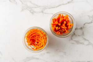Adding sliced carrots to a jar.