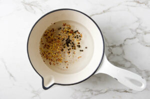 Making a brine with vinegar and spices for carrots.