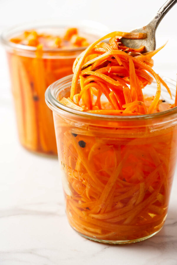Lifting pickled carrot strips out of a jar.
