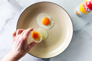 Adding an egg to a hot skillet.