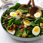 Tossing a spinach salad in hot bacon dressing.
