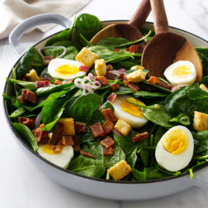 Tossing a spinach salad in hot bacon dressing.