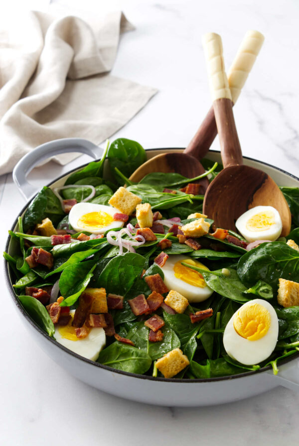A hot spinach salad tossed with bacon dressing and hard boiled eggs.