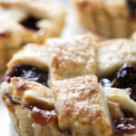 Mini dried cherry tarts with golden lattice crust and berry filling, close-up view.