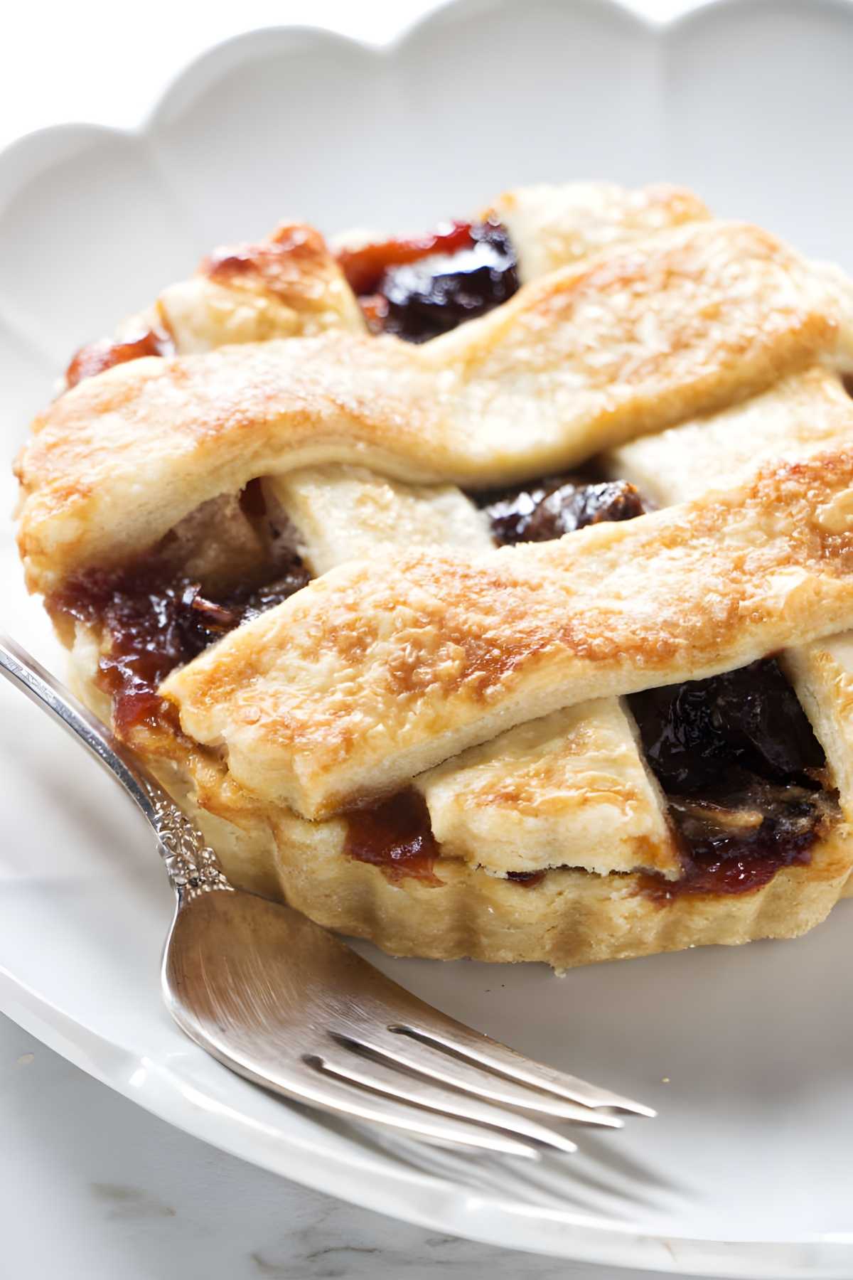 Mini lattice-topped fruit tarts on white plate.