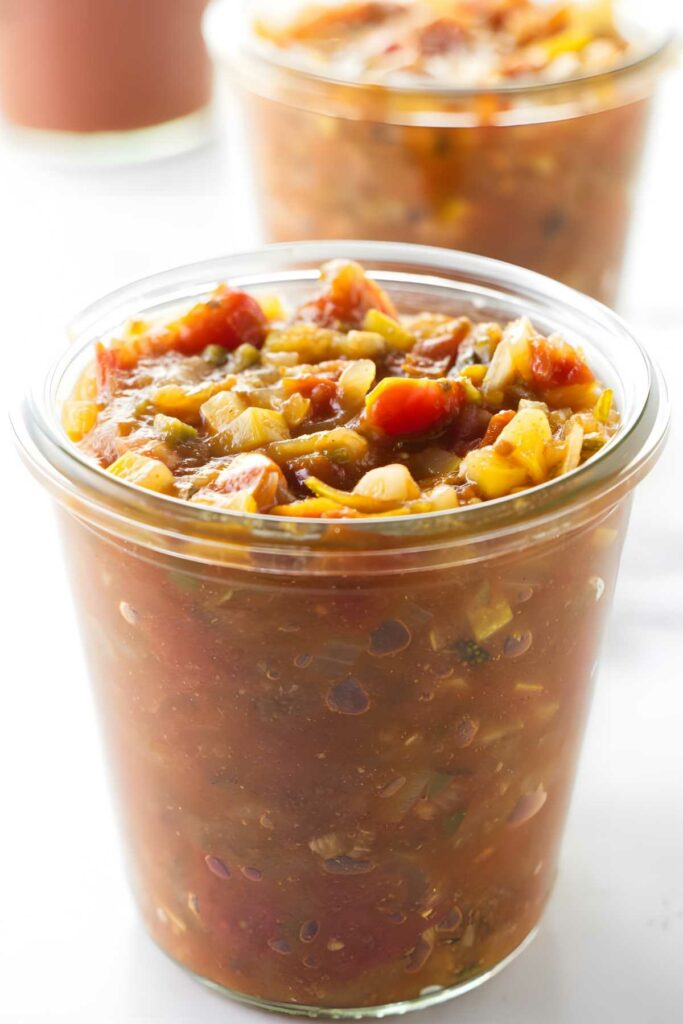 Close-up of a glass jar filled with colorful, chunky homemade salsa.