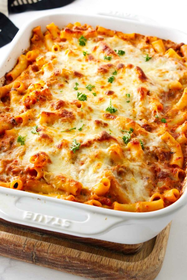 A white baking dish filled with baked ziti pasta with cheese.