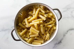 Draining ziti pasta in a colander.
