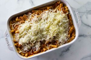 Topping the creamy ziti pasta with cheese.