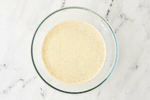 Whisking an egg and milk custard in a bowl.