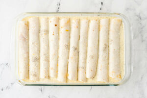 Adding the egg custard to the casserole to seep around the enchiladas.