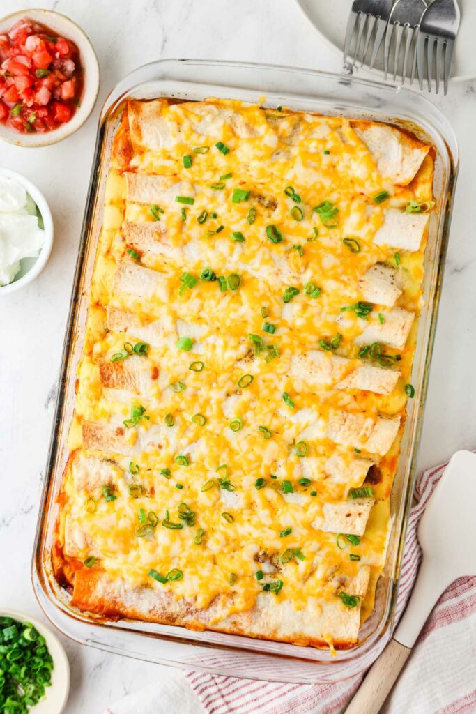 A breakfast enchilada casserole in a dish next to pico de gallo.