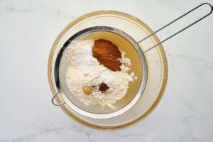 Sifting the dry ingredients into the carrot cake batter.