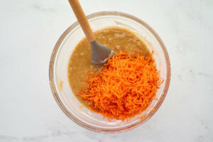 Stirring shredded carrots into cake batter.
