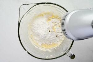 Beating powdered sugar into the frosting.