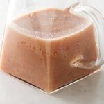 A glass pitcher filled with hot bacon dressing for salad.