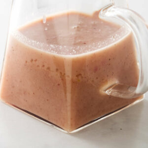 A glass pitcher filled with hot bacon dressing for salad.