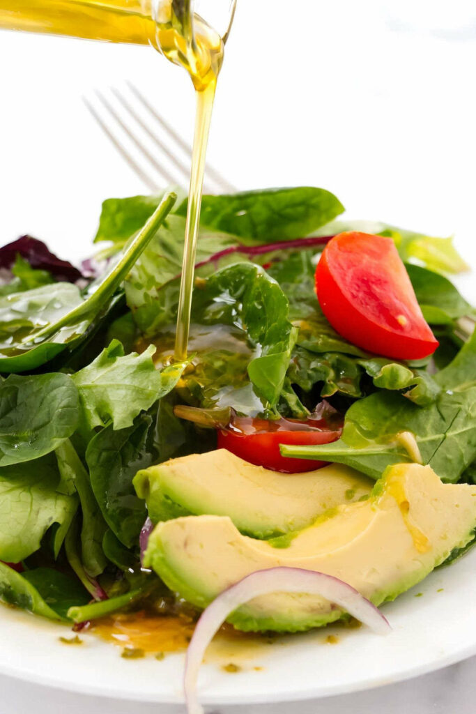 Pouring a vinaigrette over a green salad.