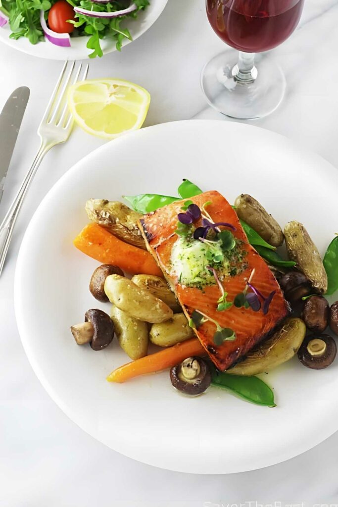 Broiled salmon with herbs, potatoes, carrots, mushrooms, and snap peas on a plate.