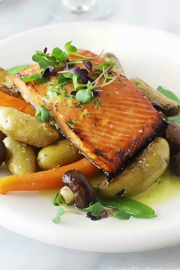 Baked salmon fillet with dill butter, potatoes, mushrooms, and snap peas.