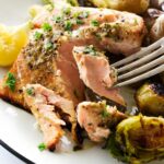 Baked salmon, roasted potatoes, and brussels sprouts on a plate with lemon.