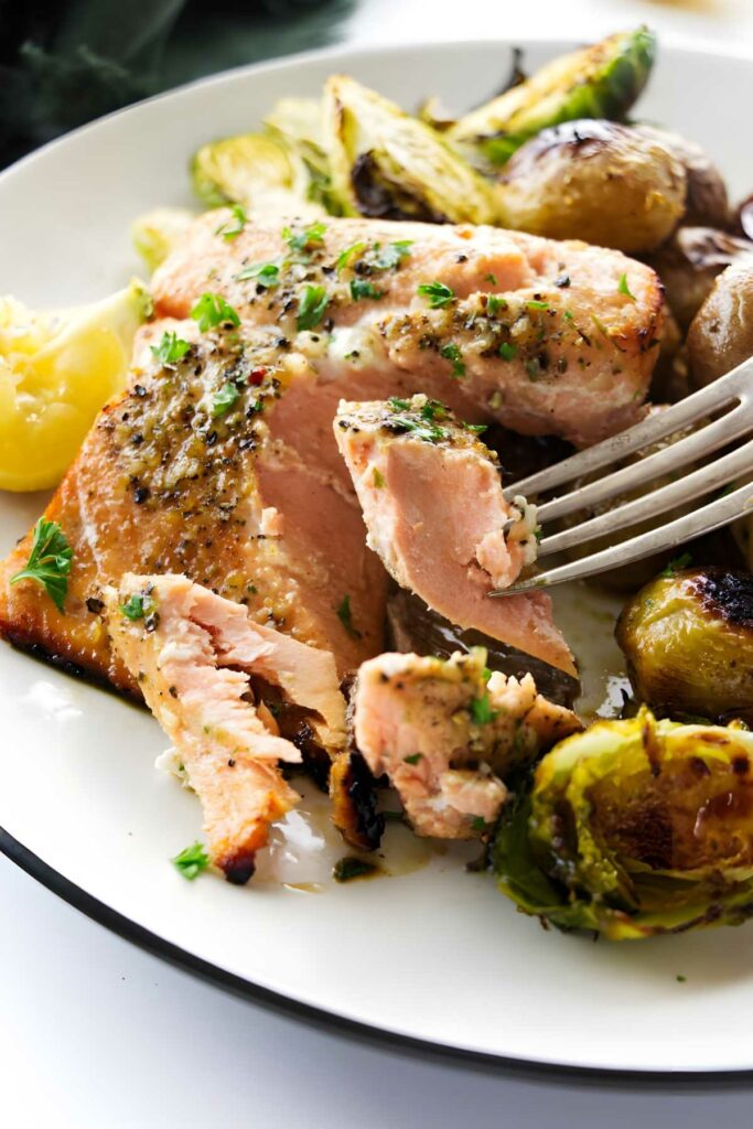Baked salmon, roasted potatoes, and brussels sprouts on a plate with lemon.