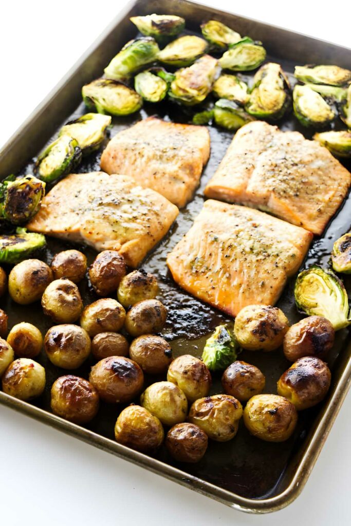 Sheet pan with cooked salmon, roasted brussels sprouts, and baby potatoes.