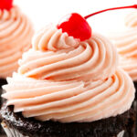 Pink maraschino cherry buttercream swirl topped with a red cherry.
