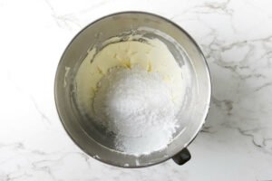 Adding powdered sugar to the mixing bowl.