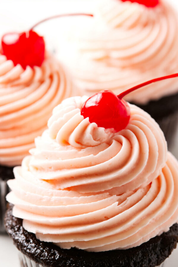 Pink maraschino cherry buttercream swirled on top of cupcakes.