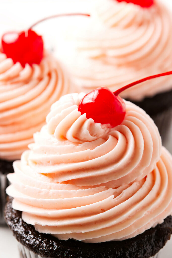 Pink maraschino cherry buttercream swirled on top of cupcakes.