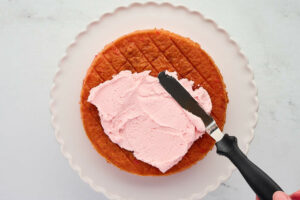 Spreading cherry buttercream on a maraschino cherry cake.