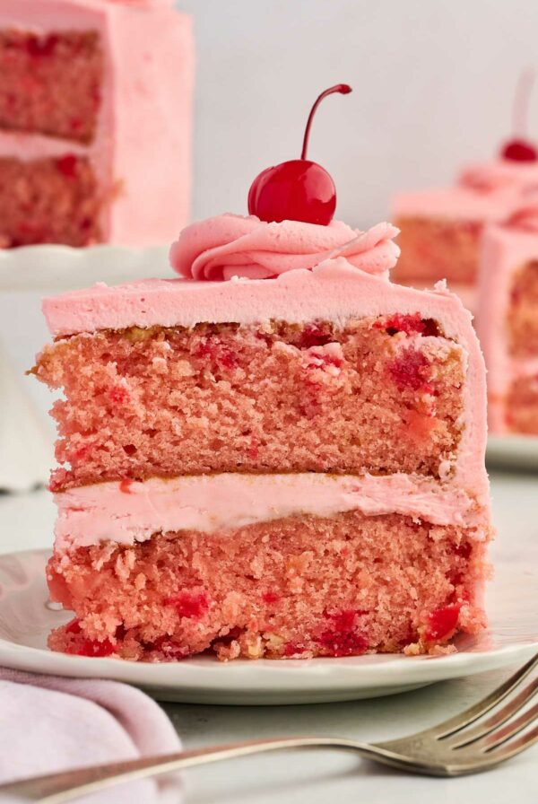 A slice of a vintage cherry chip cake with a maraschino cherry on top.