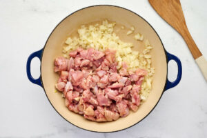 Adding the chicken pieces to the skillet to brown.
