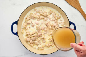 Adding the chicken broth to the skillet.