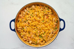 Topping the chicken and rice dinner with shredded cheese.